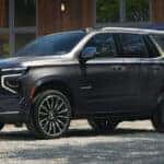 2025 Chevrolet Tahoe parked in a driveway and a man loading the trunk