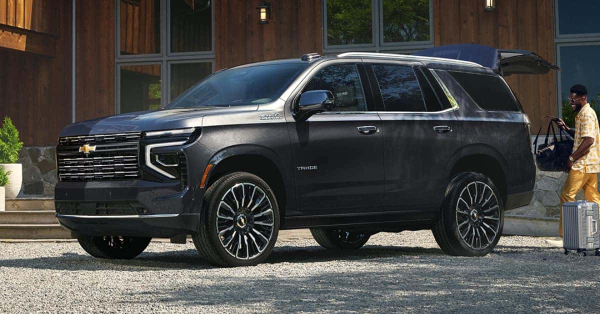 2025 Chevrolet Tahoe parked in a driveway and a man loading the trunk
