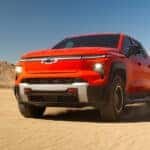 A red 2026 Chevrolet Silverado EV on a sandy area