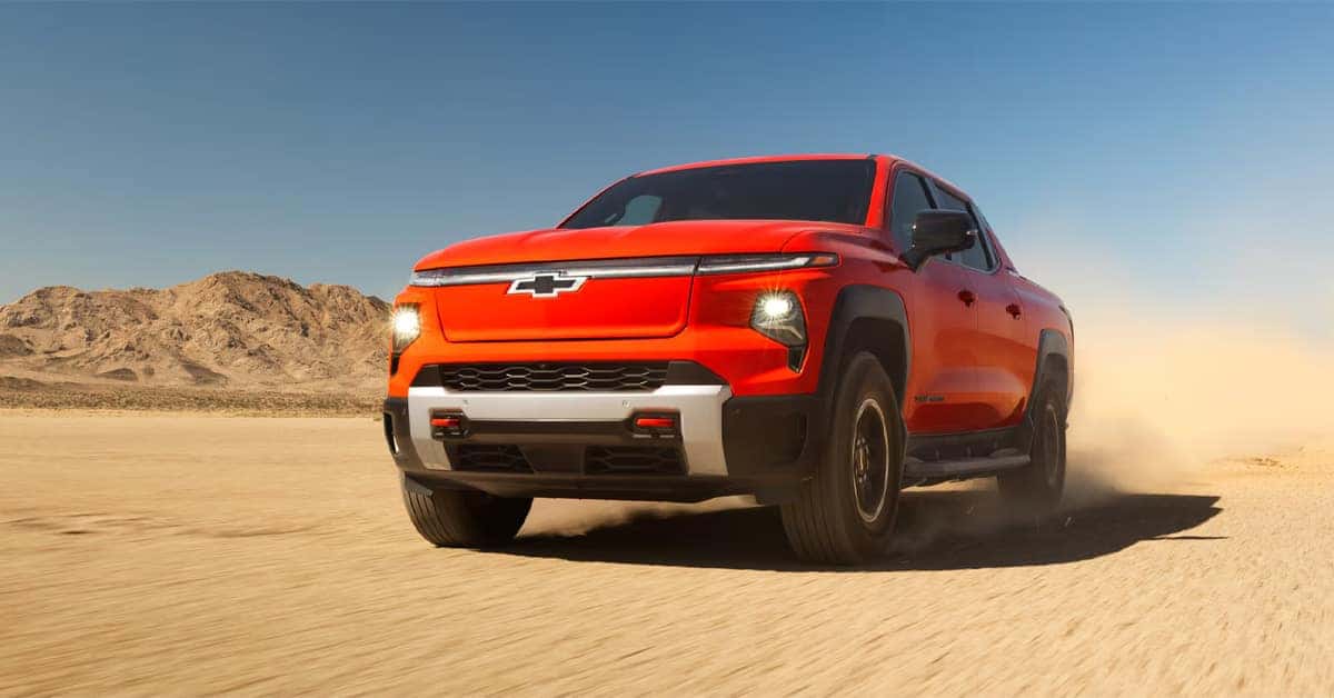 A red 2026 Chevrolet Silverado EV on a sandy area