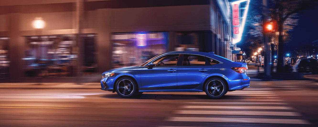 Side profile of a Honda Civic Sedan passing a crosswalk in a city setting