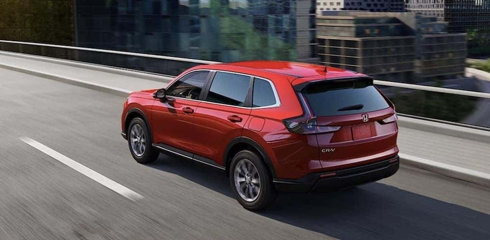 A red 2026 Honda CR-V SUV driving over a bridge