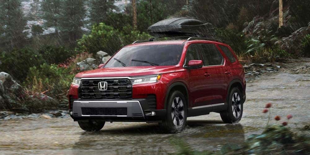 A red 2026 Honda Pilot SUV driving in the rain