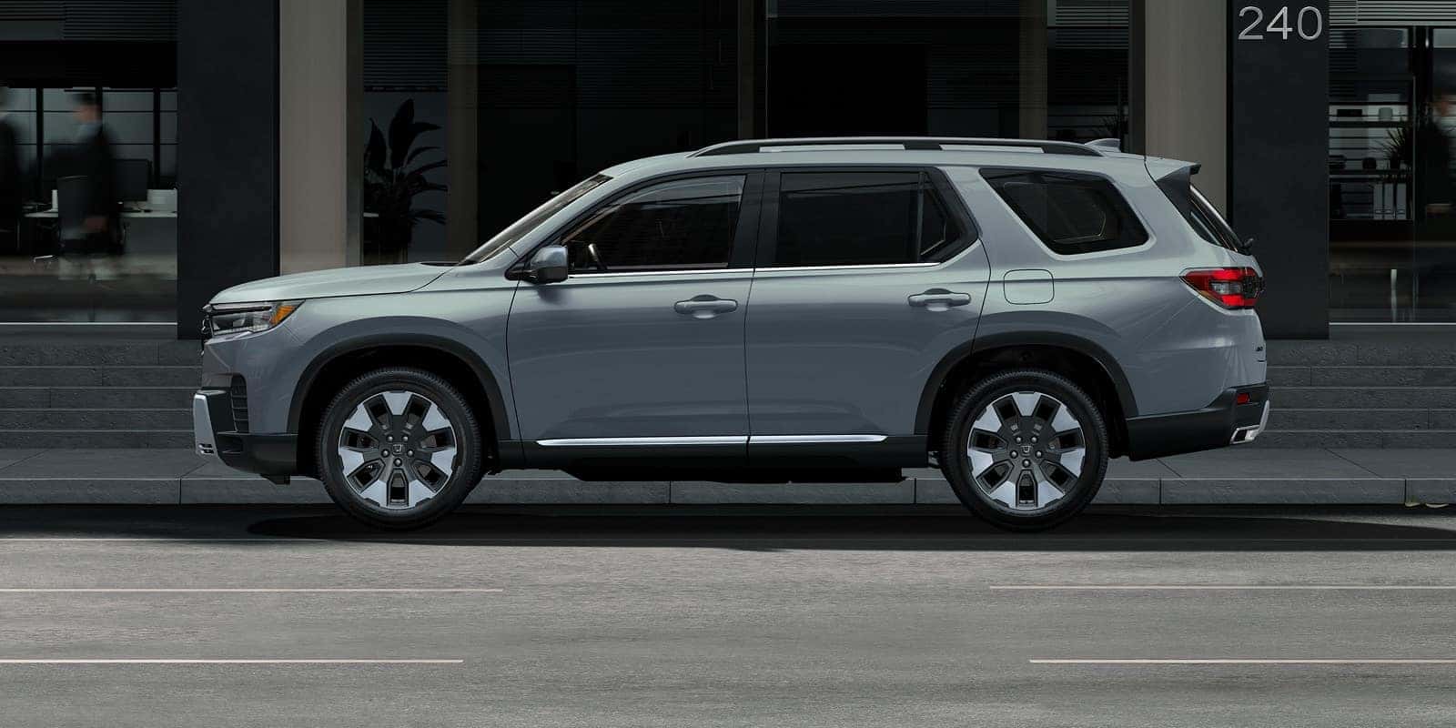 A side view of a gray 2026 Honda Pilot SUV parked on a city street