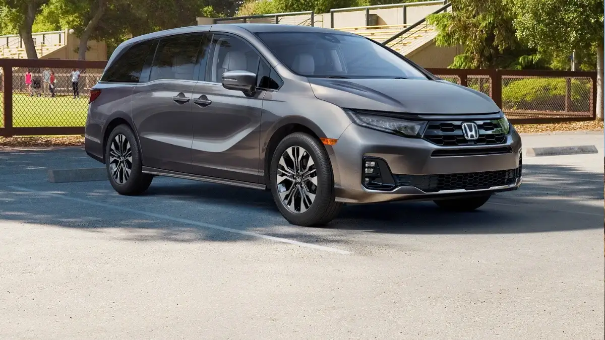 A gray Honda Odyssey minivan parked at an athletic field