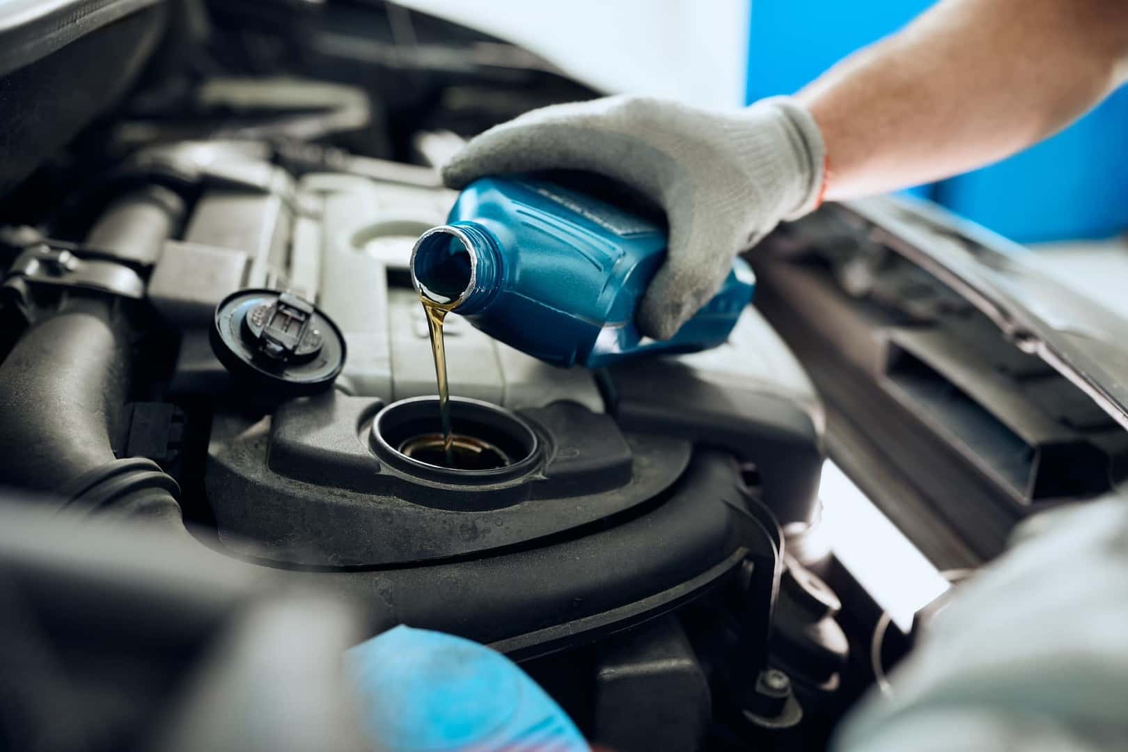 Service technician pouring motor oil into vehicle