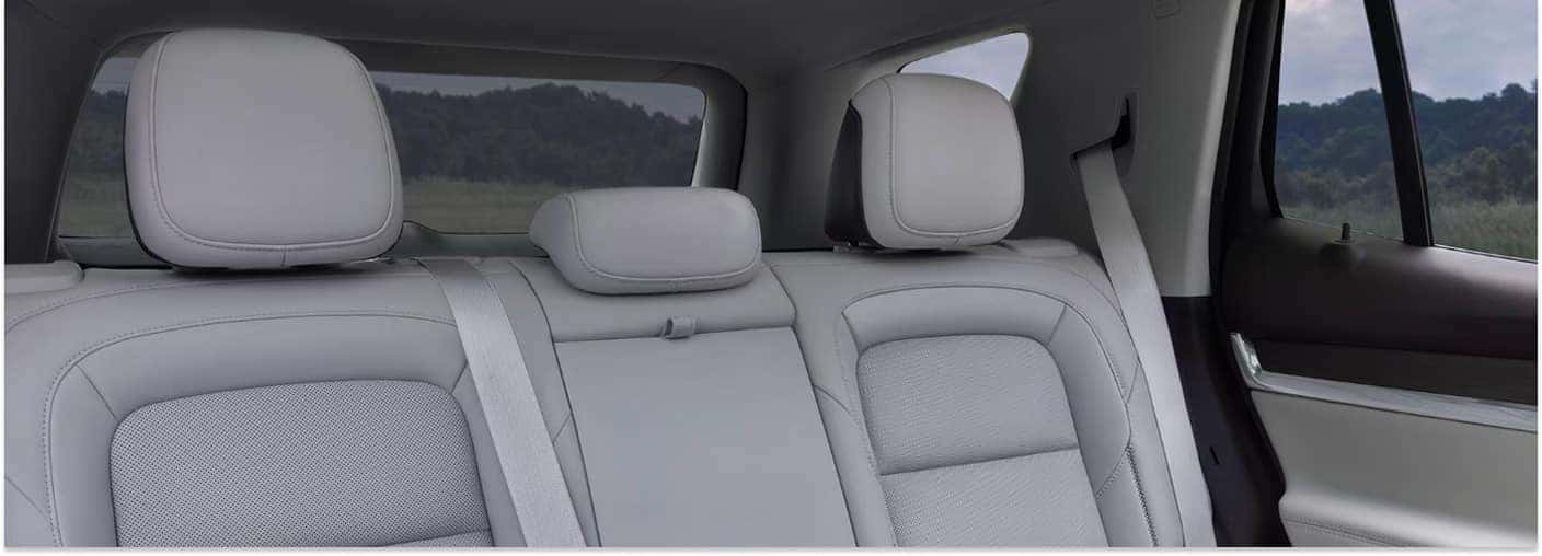 The rear passenger seats of a 2026 GMC Terrain showcase light gray perforated upholstery with adjustable headrests and integrated seatbelts.