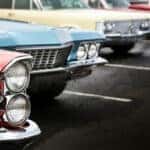 row of classic cars lined up in a parking lot for a car show
