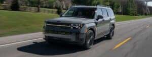 grey 2025 hyundai santa fe driving down a road