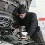 Man in Black Jacket and Black Knit Cap Inspecting Car Engine