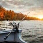 fishing rod hanging over edge of boat on a lake