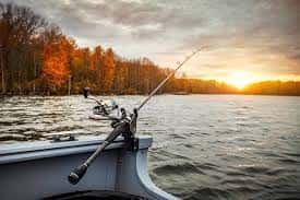 fishing rod hanging over edge of boat on a lake