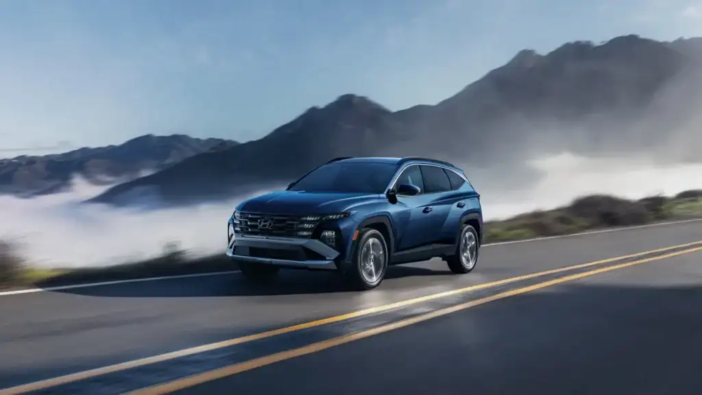 blue hyundai tucson suv driving on highway with mountains in background