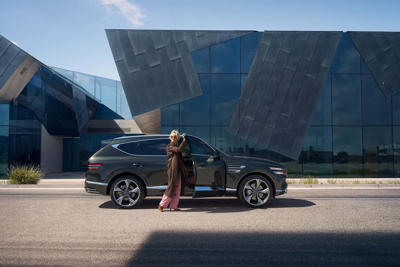 woman opening door to 2025 GV80 exterior green luxury SUV
