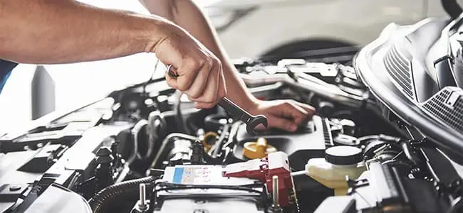 A service technician working on a vehicle's engine