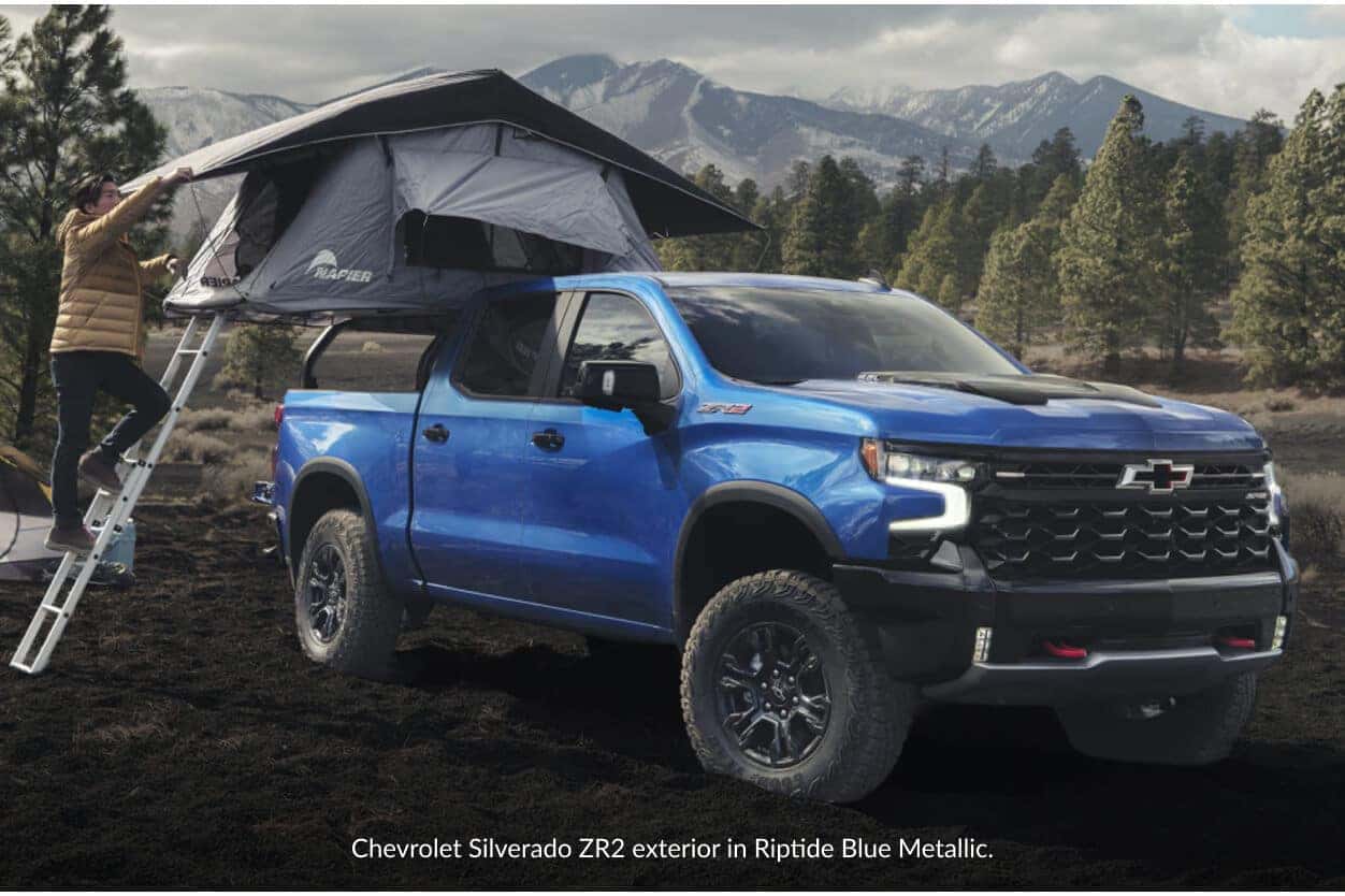 Front three-quarter view of a blue Chevrolet Silverado ZR2 with a bed-mounted Napier rooftop tent.