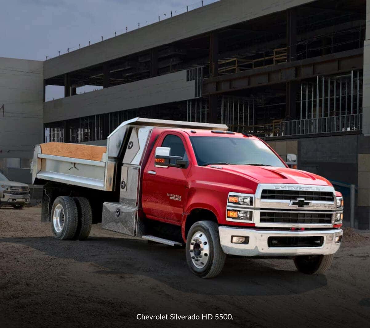 Three-quarter view of a red Chevrolet Silverado 5500 HD dump truck parked at a construction site.