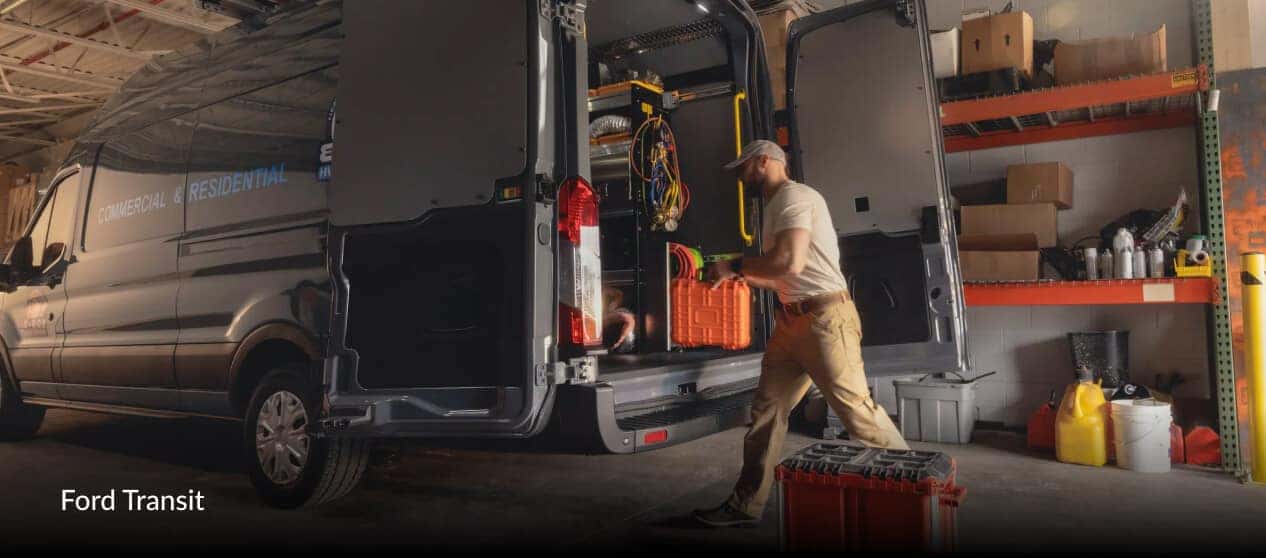 2025 Ford Transit Cargo Van High Roof in Carbonized Gray Metallic as a worker loads equipment inside a service garage.