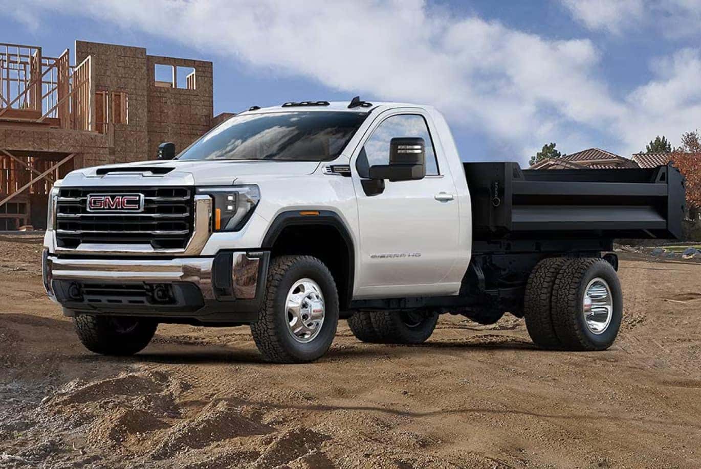 A GMC flatbed utility truck parked in a sandy construction site.