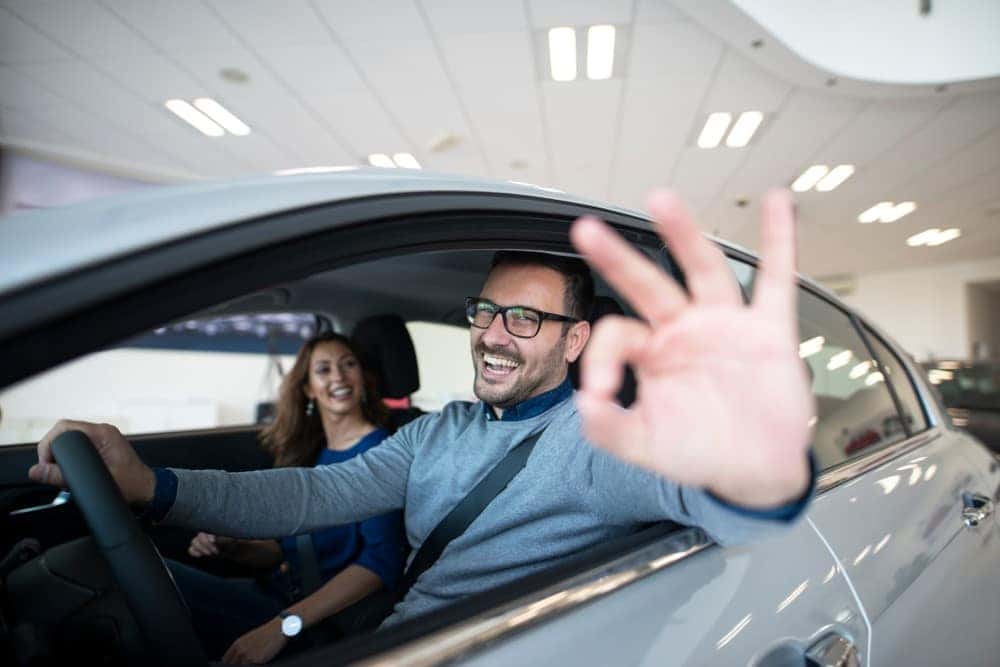 A man showing the 'ok' hand symbol while sitting in a certified pre-owned Honda.