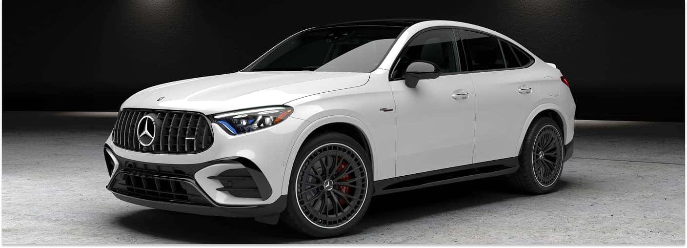 Front three-quarter view of a white 2026 Mercedes-Benz GLC SUV in a dark studio setting.