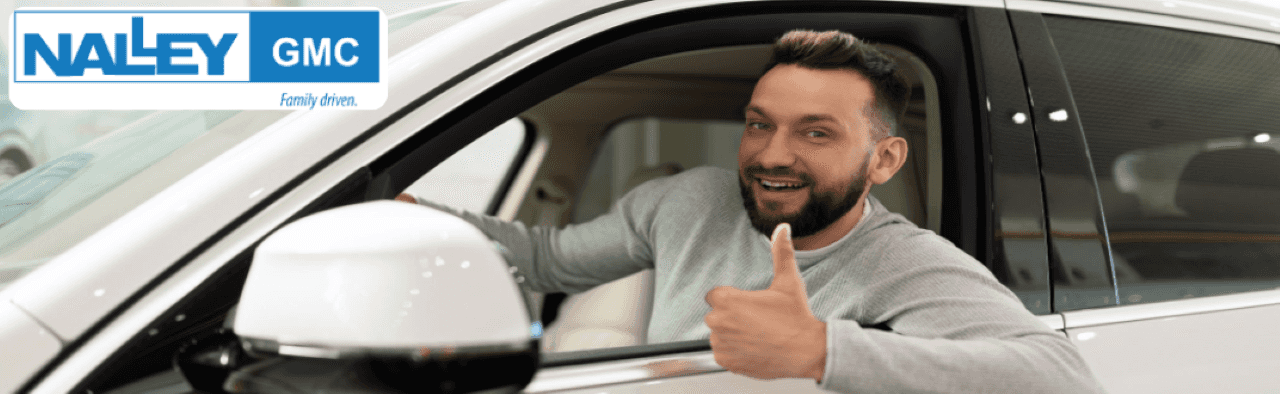 A happy customer driving home in a used SUV from Nalley GMC