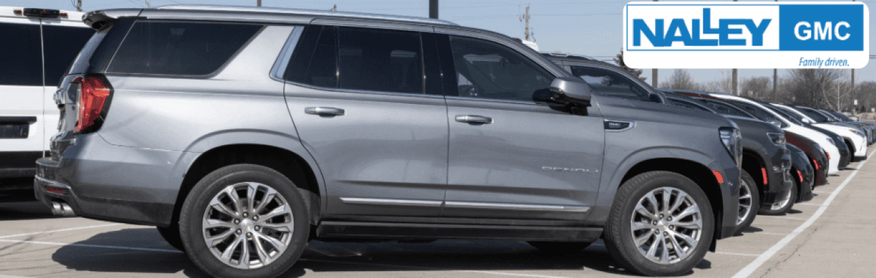 A lineup of used cars for sale at Nalley GMC dealership in Brunswick, GA, with friendly staff in the background.