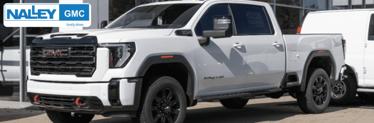 A smiling car buyer shaking hands with a Nalley GMC salesperson next to a Carfax® used car.