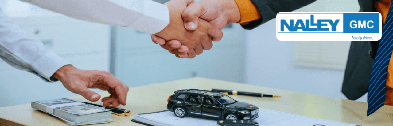 Customer reviewing trade-in offer with finance manager at Nalley Brunswick GMC showroom.