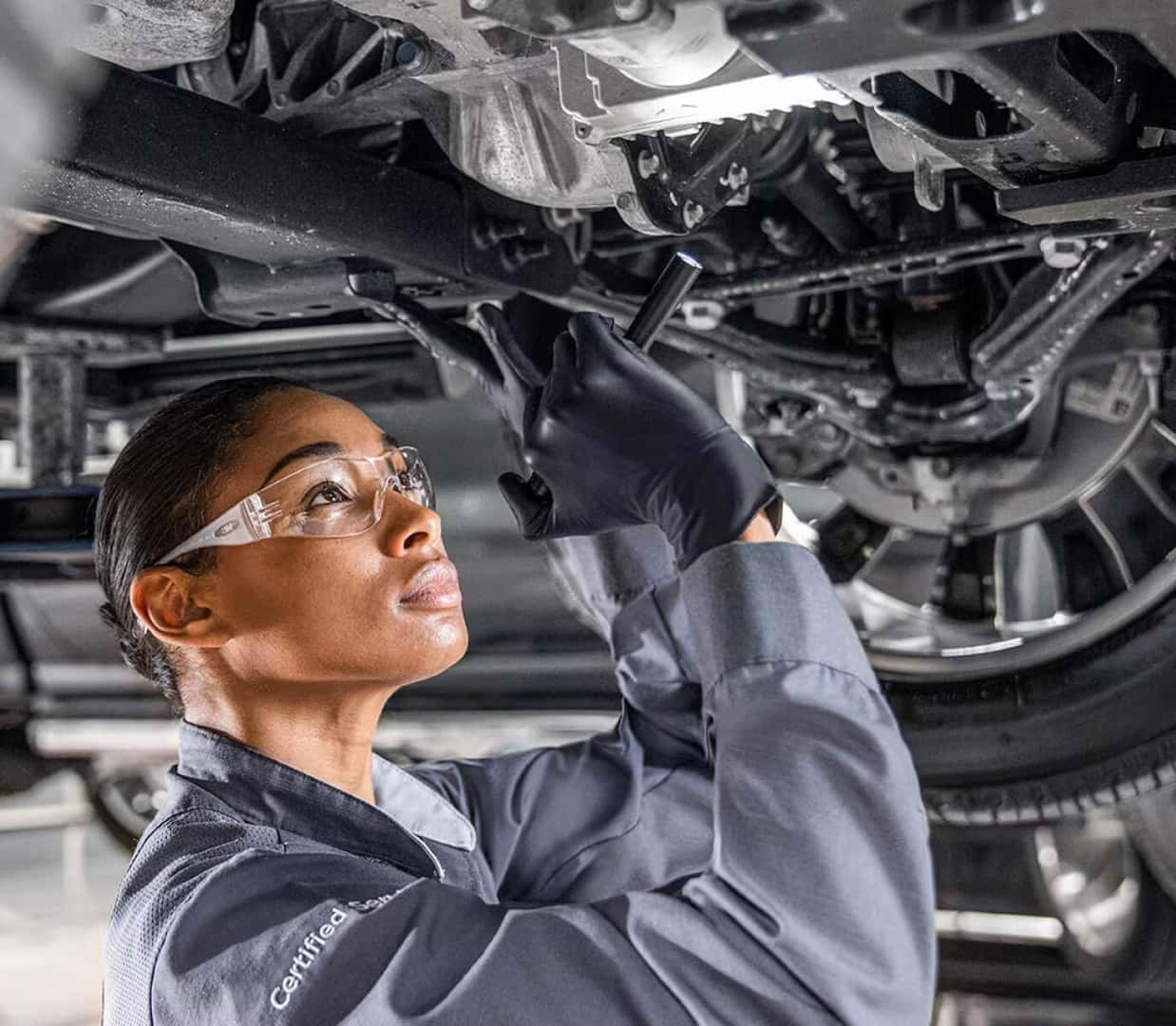 A GM Certified Technician inspects the underside of a vehicle.