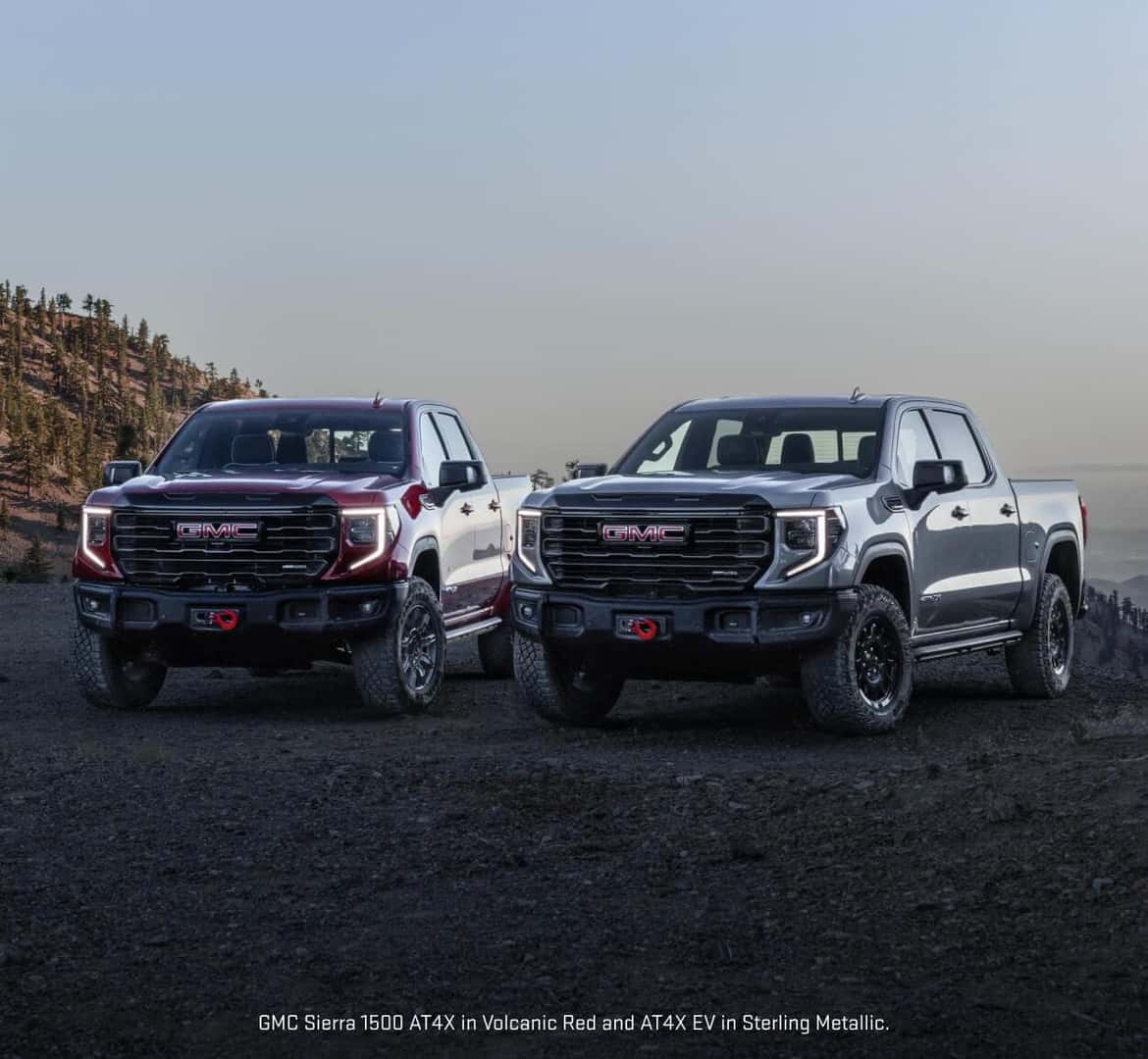 Front view lineup of a GMC Sierra 1500 AT4X in Volcanic Red Tintcoat and an AT4X EV in Sterling Metallic parked.