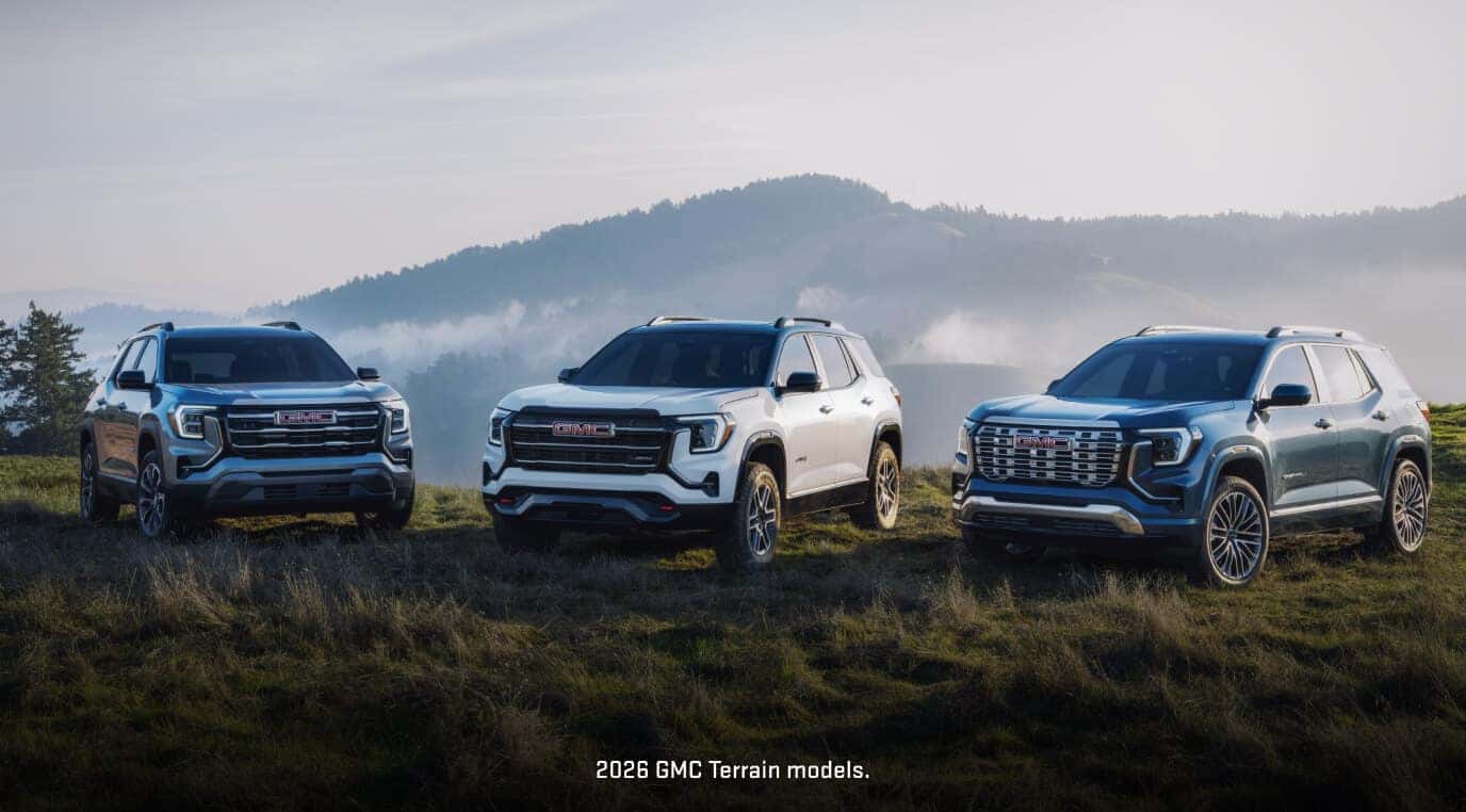 Front three-quarter lineup showcasing three distinct 2026 GMC Terrain trim levels parked on a grassy hilltop.