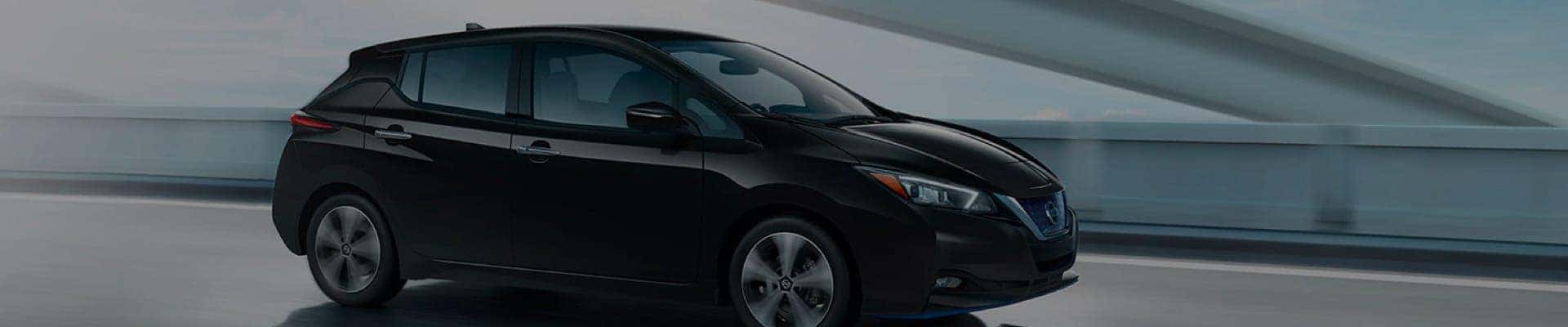 Black Nissan LEAF driving through city at night