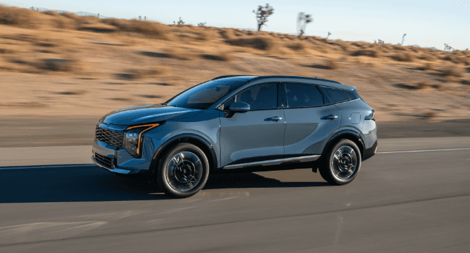 2026 Kia Sportage Hybrid driving quickly on road.