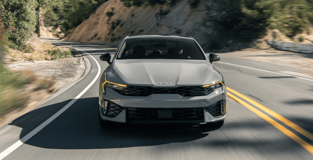 2026 Kia K5 sedan front view driving on curvy mountain road