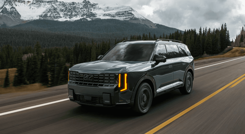 2027 Kia Telluride SUV driving on highway with mountain backdrop