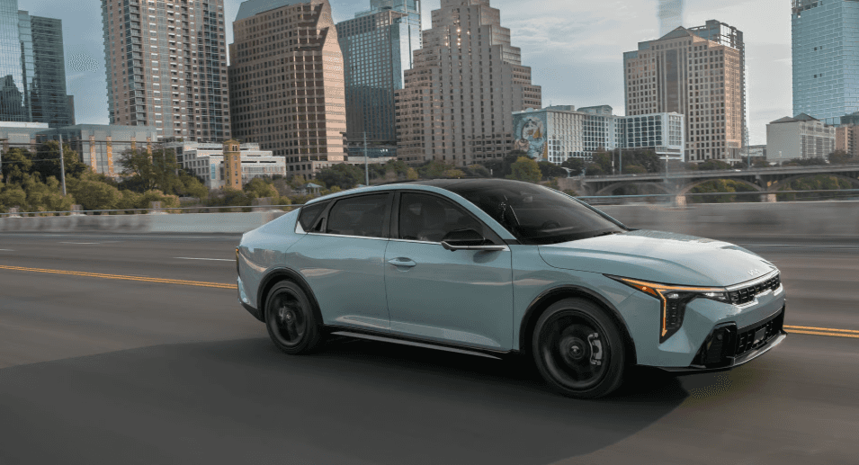 Light Blue 2026 Kia K4 on expressway with the city background in the distance.