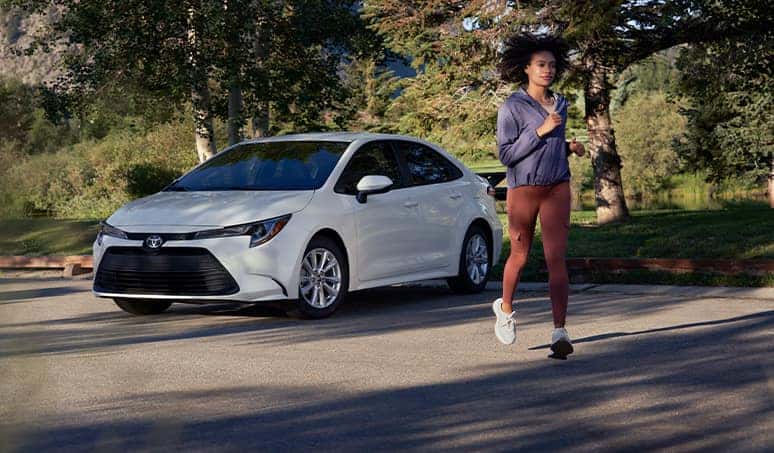 Most Fuel Efficient Toyota Models at Palmiero Toyota | Woman running past a parked Toyota Corolla
