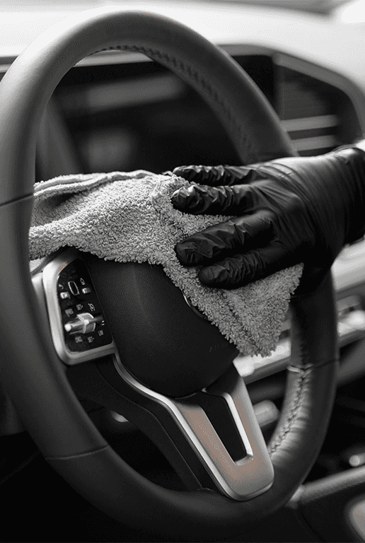 Accessories that help keep your Toyota protected at Palmiero Toyota in Meadville, PA | Person wearing black gloves and using a microfiber towel to clean their steering wheel