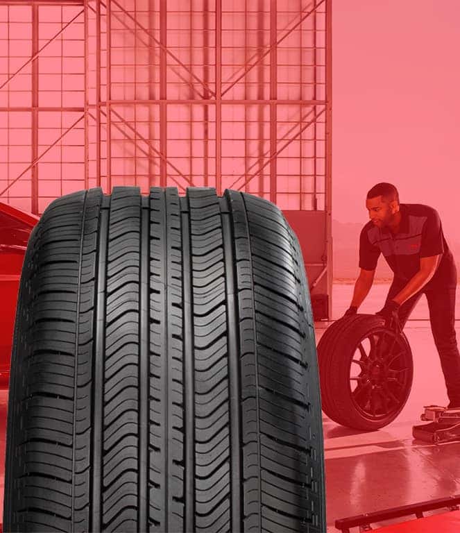 The Cold Facts of Winter Tires | Palmiero Toyota in Meadville, PA | Close up detail of new winter tires with a mechanic rolling new tire in the background