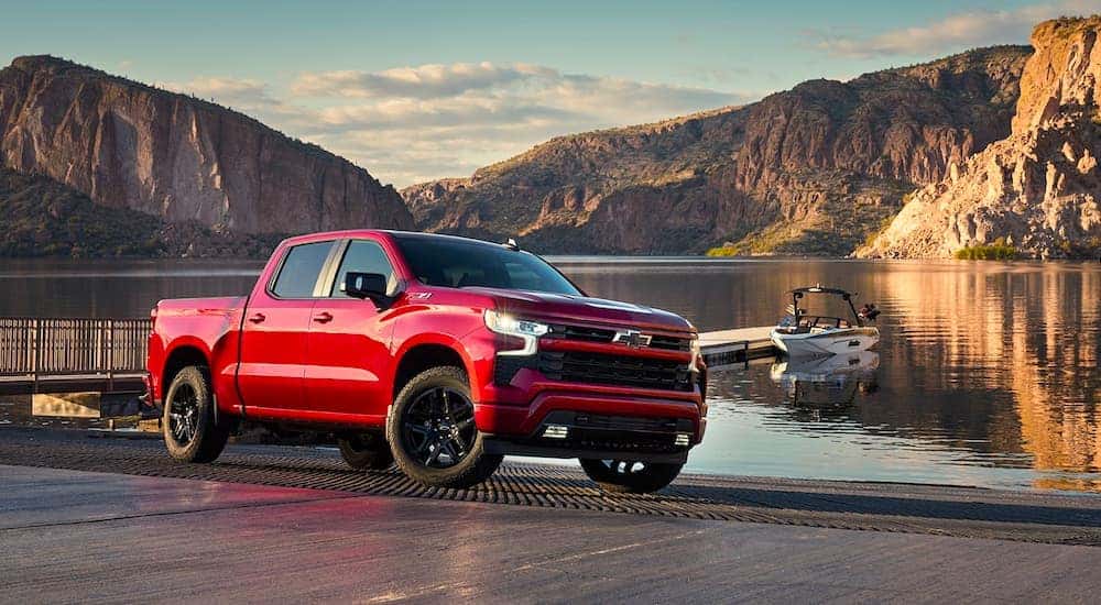 A red 2023 Chevy Silverado 1500 Z71 is shown in front of a lake.