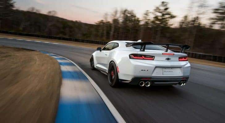 A white 2023 Chevy Camaro ZL1 is shown from the rear driving on a track.