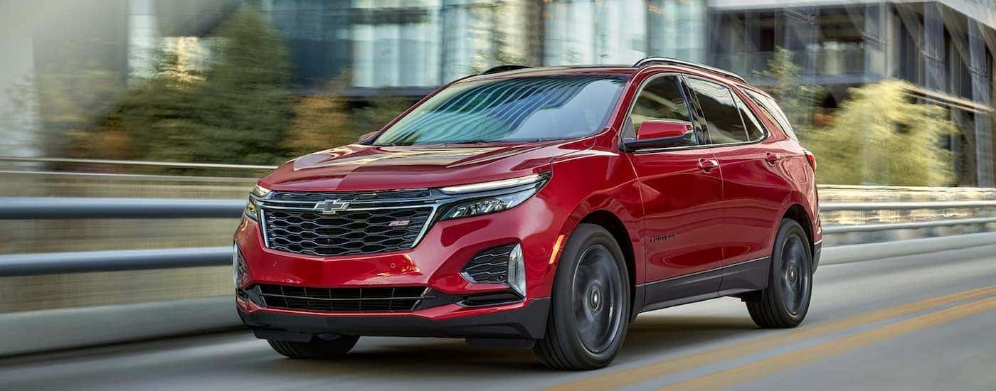 A red 2023 Chevy Equinox RS is shown on a highway after leaving a Chevrolet dealer near you.