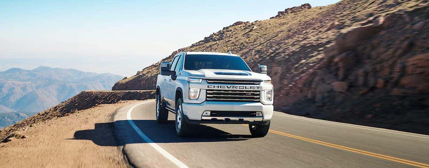 A white 2023 Chevy Silverado 3500HD Z71 is shown driving on a mountain highway.