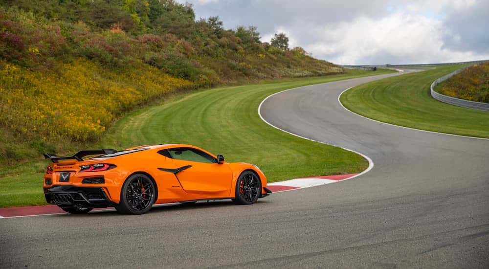 An orange 2023 Chevy Corvette Z06 is shown driving on a racetrack.