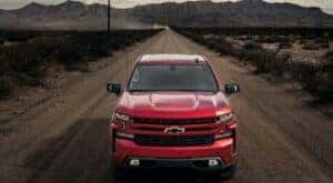 A red 2023 Chevy Silverado 1500 RST is shown from the front driving on a dirt path.