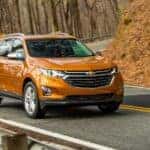 An orange 2018 Chevy Equinox is shown driving on a road after visiting a used Chevy dealer near Murray, UT.