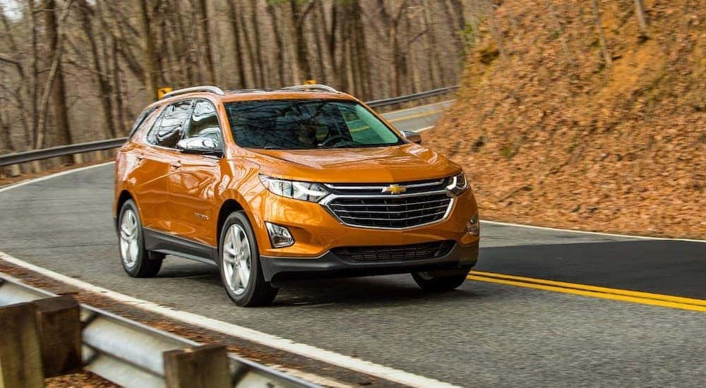 An orange 2018 Chevy Equinox is shown driving on a road after visiting a used Chevy dealer near Murray, UT.