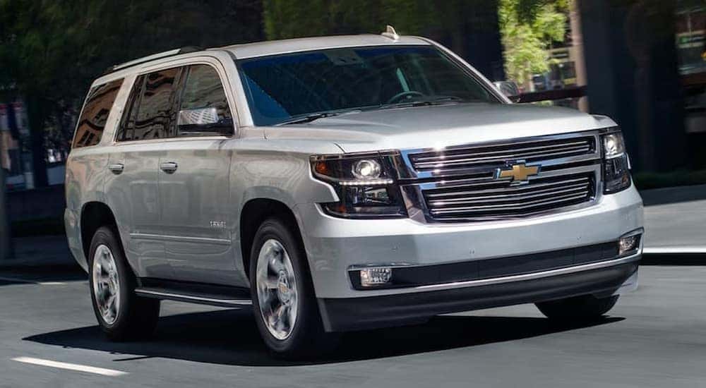 A silver 2019 Chevy Tahoe is shown driving on a city road.