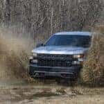A silver 2020 Chevy Silverado 1500 Z71 Trail Boss is shown from the front while driving through mud.